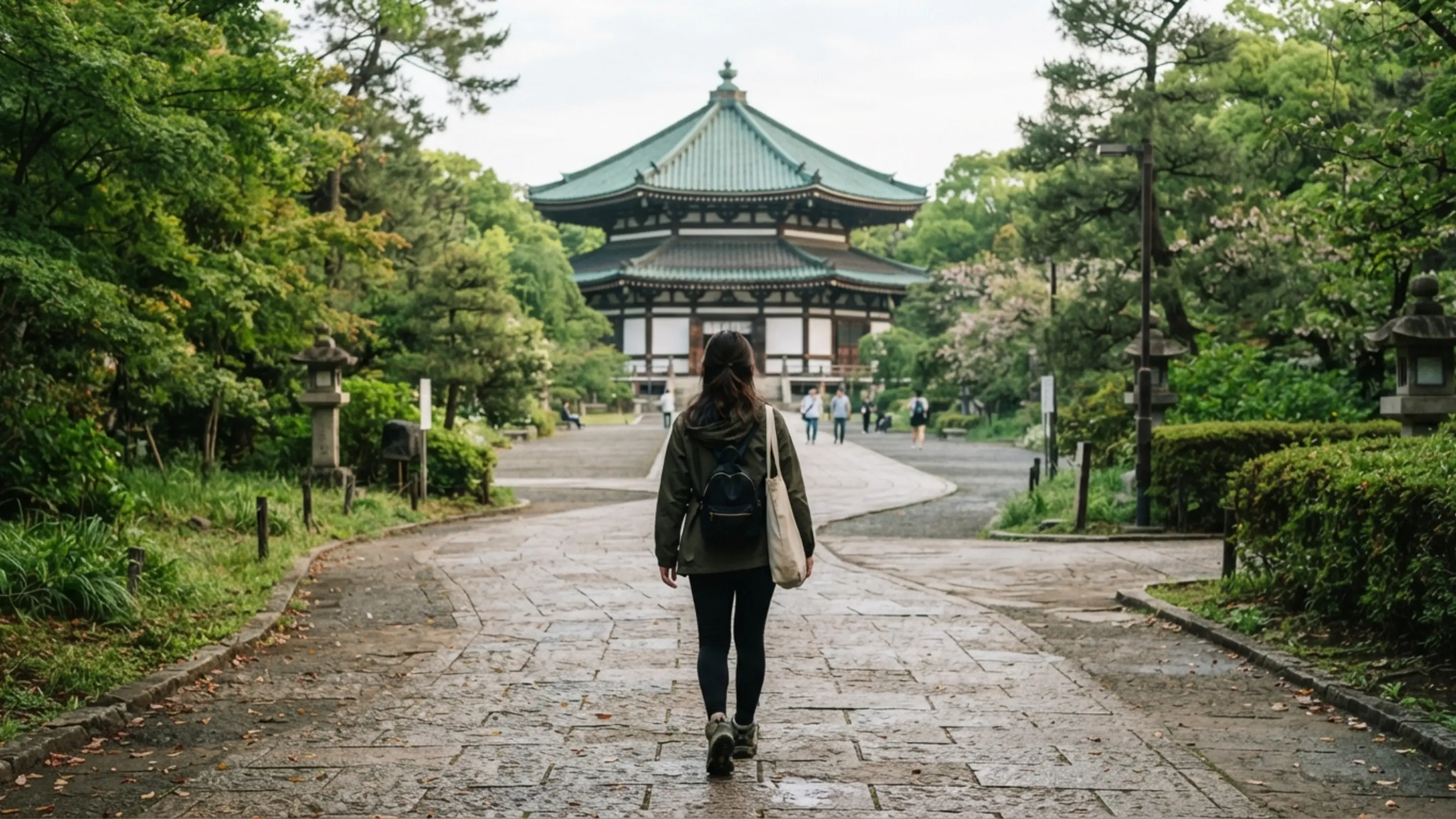 緑に囲まれた北の丸公園の道を歩いて日本武道館へ向かう人の後ろ姿