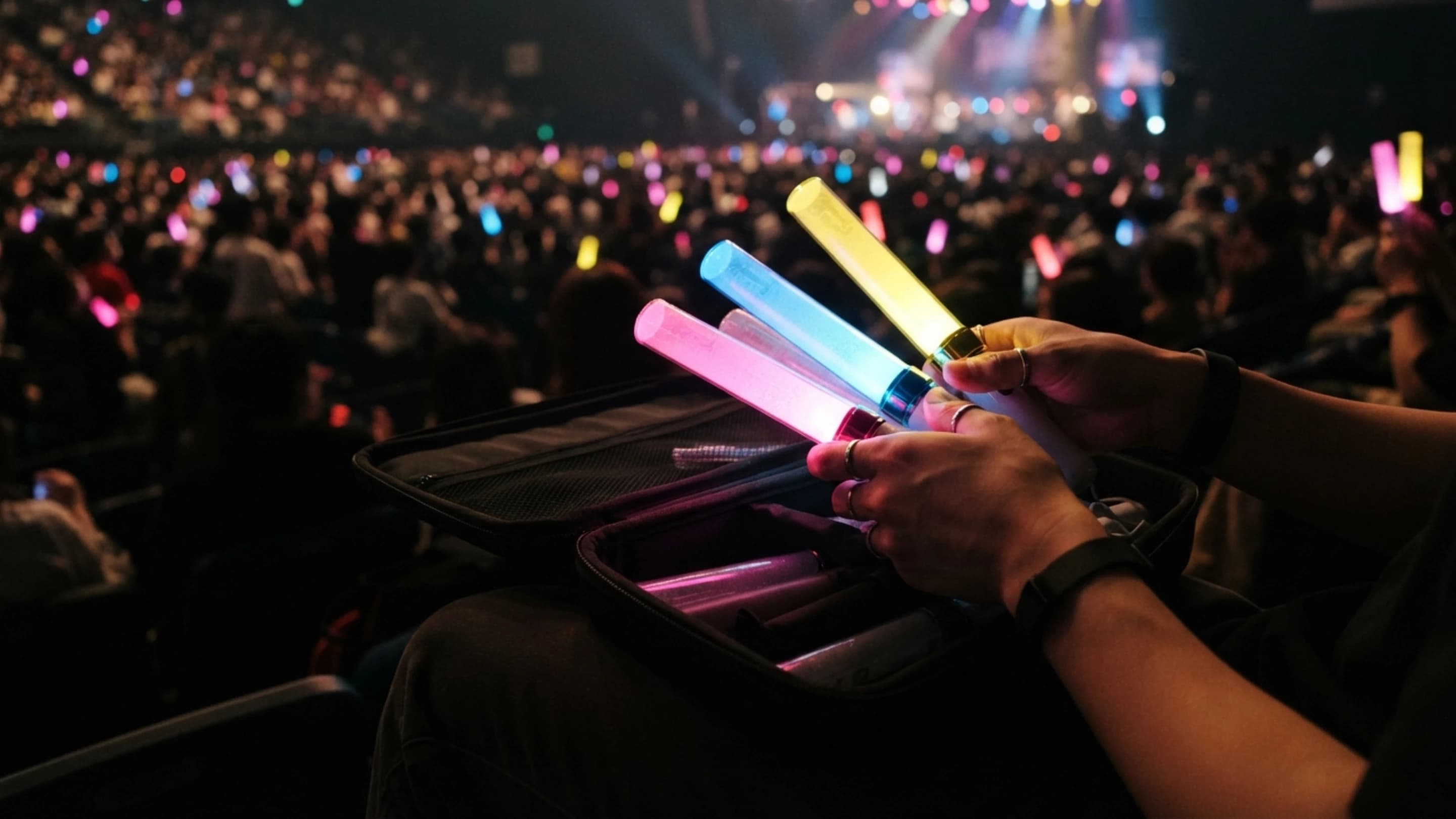 ライブ会場で開演前、ケースから発光する推し色のペンライトを取り出す手元の様子